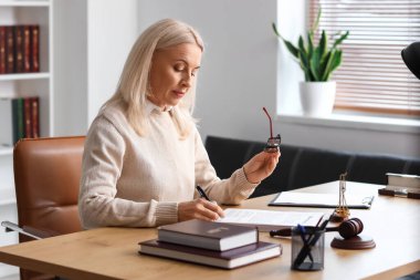 Olgun kadın yargıç mahkeme masasında belge imzalıyor.