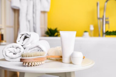 Kozmetik ürünler, masaj için fırça ve banyo masasındaki havlular.