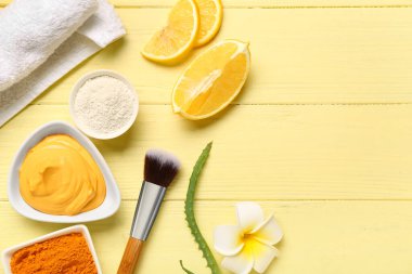 Tabakta zerdeçal maskesi, toz, makyaj fırçası ve çiçek renginde ahşap arka planda kompozisyon