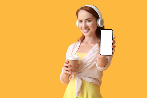 Jonge Roodharige Vrouw Hoofdtelefoon Met Kopje Koffie Mobiele Telefoon Gele — Stockfoto
