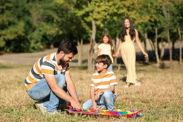 Küçük çocuk ve babası açık havada uçurtma taşıyor.
