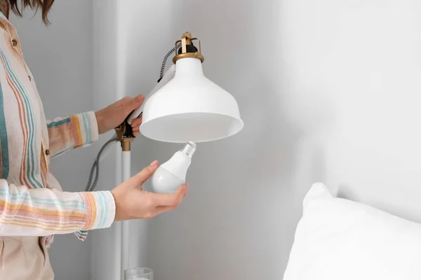 Woman Changing Light Bulb Lamp Bed Home — Stock Photo, Image