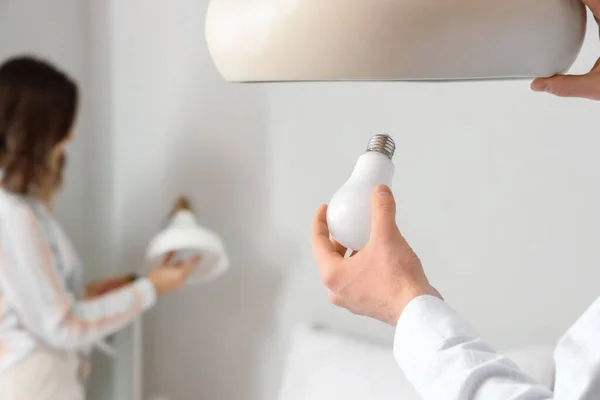 Man changing light bulb in hanging lamp at home, closeup