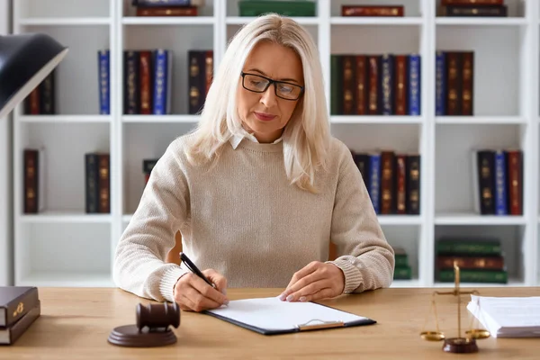 Mahkeme masasında belgelerle çalışan olgun bir kadın yargıç.