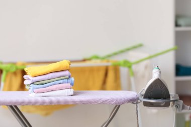 Farklı giysiler ve elektrikli ütü yığını var.
