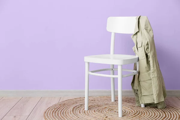 部屋の中のバイオレット壁の近くの椅子とスタイリッシュなジャケット — ストック写真
