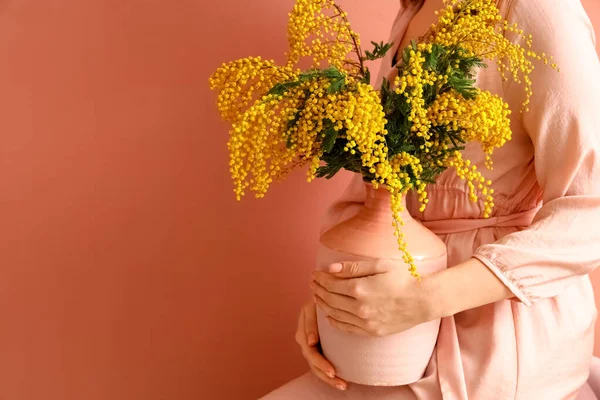 色の背景にミモザ花と花瓶を保持女性 — ストック写真