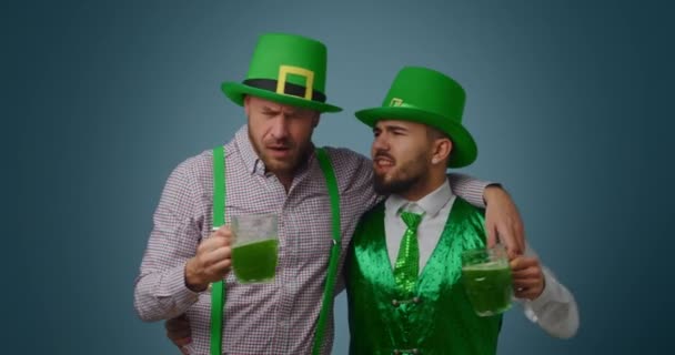 飲んで髭を生やした男たちが色を背景に緑色のビールを飲みながら歌っている 聖パトリックの日お祝い — ストック動画