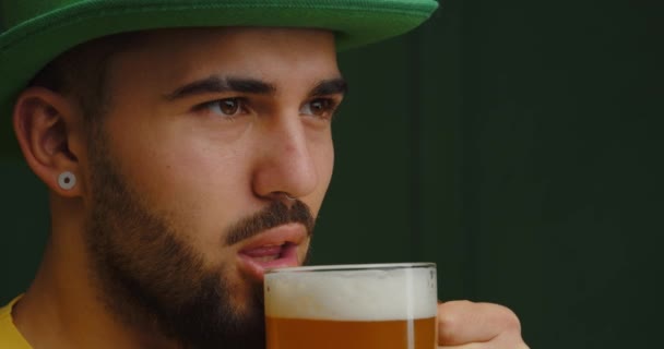 英俊的大胡子男人在深色背景下喝啤酒 圣帕特里克日庆祝活动 — 图库视频影像