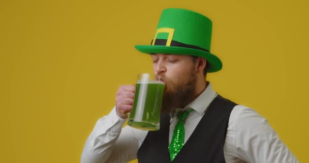 黄色の背景に緑のビールを飲むハンサムな髭の男 聖パトリックの日お祝い — ストック動画