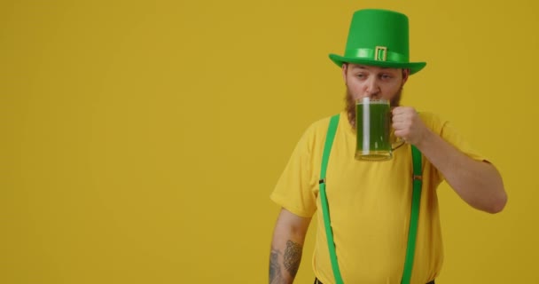 緑のビールを飲み 黄色の背景に親指を示すハンサムな髭の男 聖パトリックの日お祝い — ストック動画