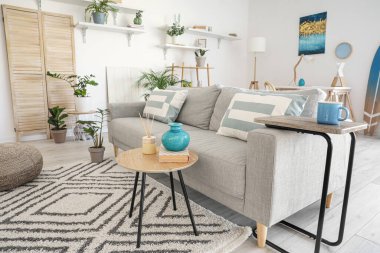 Modern oturma odasının iç kısımlarında çiçekli şık gri kanepe.