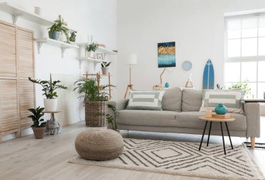 Modern oturma odasının iç kısımlarında çiçekli şık gri kanepe.