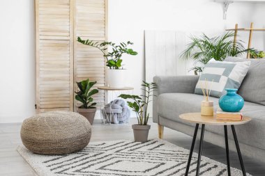 Modern oturma odasının iç kısımlarında çiçekli şık gri kanepe.