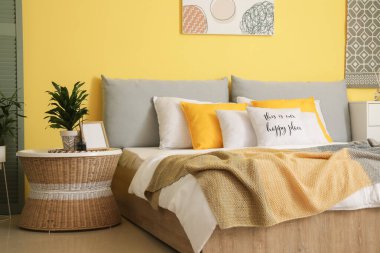 Sarı duvarlı modern yatak odasının şık iç mimarisi.