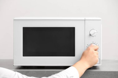 Masanın üzerinde modern mikrodalga fırını kullanan kadın, yakın plan.