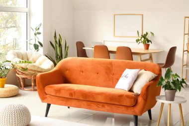 Kırmızı kanepe ve çiçeklerle aydınlık oturma odasının içinde.