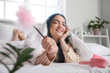 Yataktaki seks dükkanından tüy çubuğu olan güzel genç bir kadın.