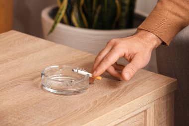 Sigara içen adam evde kül tablası kullanıyor, yakın plan.