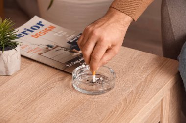 Sigara içen adam evde kül tablası kullanıyor, yakın plan.