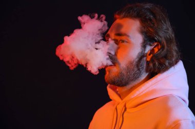 Siyah arka planda sigara içen genç adam