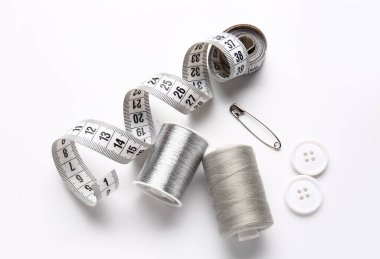 Ölçüm bandı ve beyaz arkaplanda düğmeleri olan iplik makaraları
