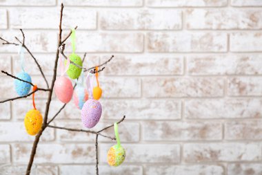 Hafif tuğla duvarın yanında farklı Paskalya yumurtaları olan ağaç dalının yakın görüntüsü