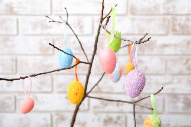 Hafif tuğla duvarın yanında farklı Paskalya yumurtaları olan ağaç dalının yakın görüntüsü