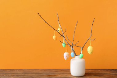 Ağaç dalları ve farklı Paskalya yumurtaları olan bir vazo.