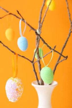Ağaç dallı vazo ve farklı renklerde Paskalya yumurtaları.