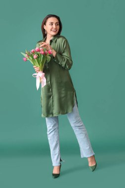 Yeşil arka planda bir buket lale olan mutlu genç bir kadın. Uluslararası Kadınlar Günü