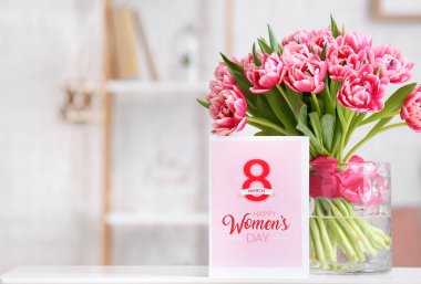 Güzel laleli vazo ve yazılı tebrik kartı. Işık odasındaki masada mutlu kadınlar günü.