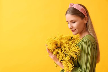 Sarı arka planda mimoza çiçekleri olan güzel bir kadın. Uluslararası Kadınlar Günü