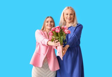 Kızı ve mavi arka planda laleleri olan olgun bir kadın. Uluslararası Kadınlar Günü