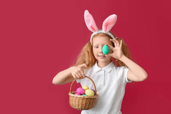 面白いです女の子とともにウサギの耳とイースターバスケット上の赤い背景 — ストック写真