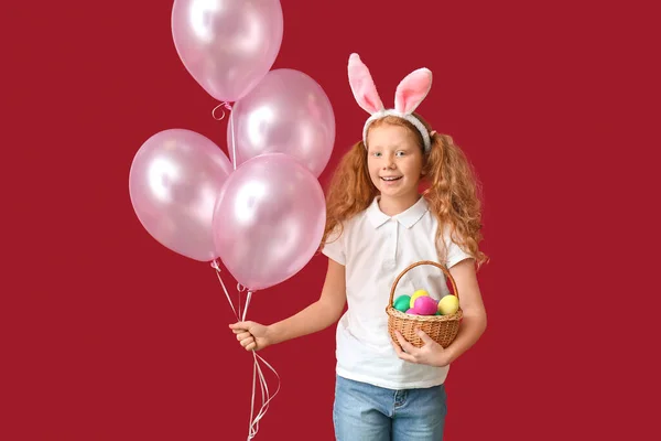 面白いです女の子とともにウサギの耳 風船や赤い背景にイースターバスケット — ストック写真