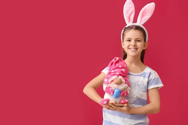赤い背景にウサギの耳とおもちゃを持つ面白い女の子 イースターのお祝い — ストック写真
