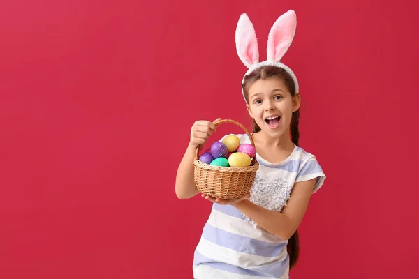 Lustige Kleine Mädchen Mit Hasenohren Und Osterkorb Auf Farbigem Hintergrund — Stockfoto