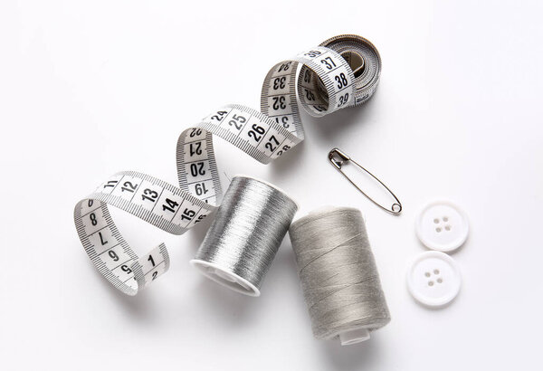 Катушки с измерительной лентой и кнопками на белом фоне