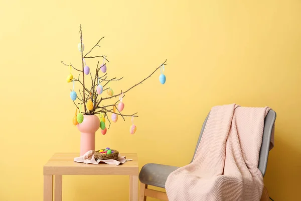 Ваза Ветвями Деревьев Пасхальные Яйца Столе Кресло Возле Цветной Стены — стоковое фото