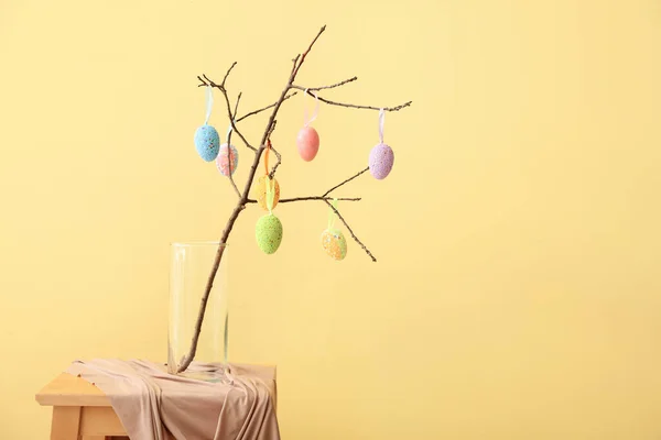 Ваза Веткой Дерева Различные Пасхальные Яйца Стуле Против Цветной Стены — стоковое фото