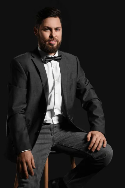 黒を背景に椅子に座っているスタイリッシュなひげそりの男 — ストック写真