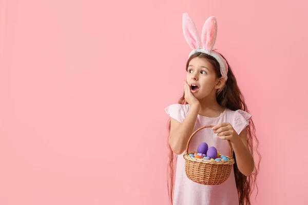 Überraschtes Kleines Mädchen Mit Hasenohren Und Osterkorb Auf Rosa Hintergrund — Stockfoto