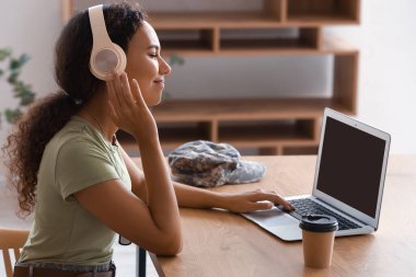 Evde müzik dinleyen, dizüstü bilgisayarı olan Afro-Amerikan bayan asker.