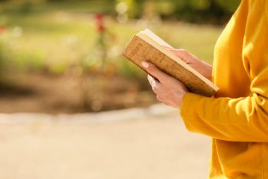 Parkta kitap okuyan güzel bir kadın, yakın plan.