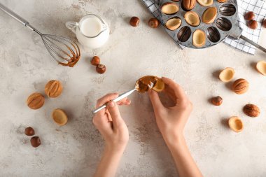 Lezzetli ceviz şekilli kurabiyeler hazırlayan bir kadın. Arka planda kaynamış konsantre süt.