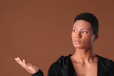 Renkli arka planda sıra dışı kaşları olan şık bir genç.