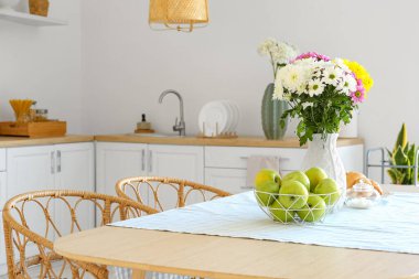 Mutfaktaki yemek masasında güzel kasımpatı çiçekleri olan vazo.