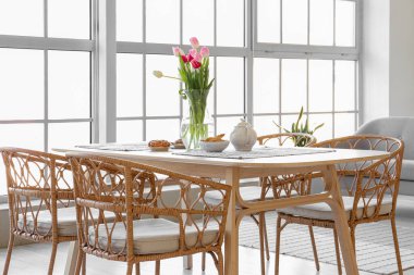 Yemek masasında güzel lale çiçekleri olan bir vazo.