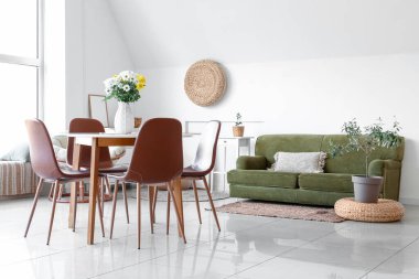 Yemek masasında güzel kasımpatı çiçekleri, rahat bir kanepe ve oda çiçekleri olan bir vazo.